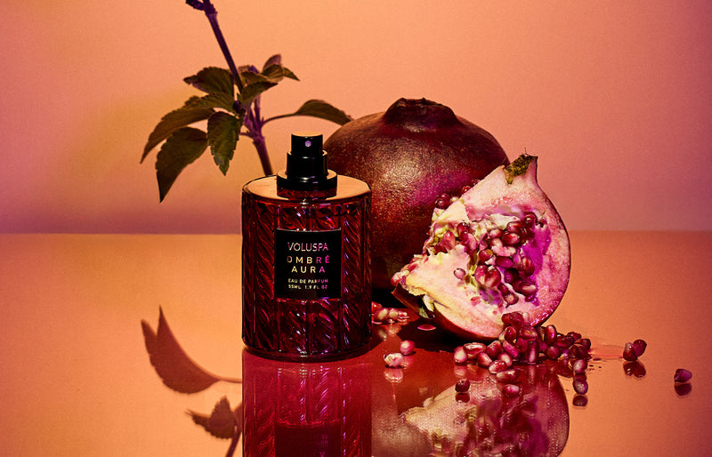 Voluspa luxury eau de parfum bottle styled with pomegranate and fresh mint, representing artisanal fragrance craftsmanship