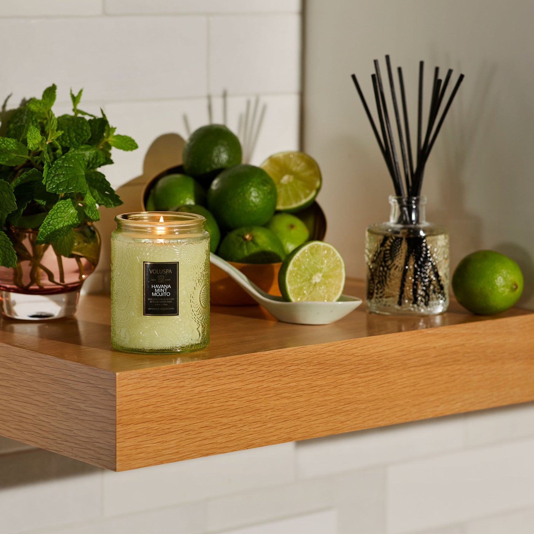 Lifestyle image of the Havana Mint Mojito Small Jar Candle lit on a counter.